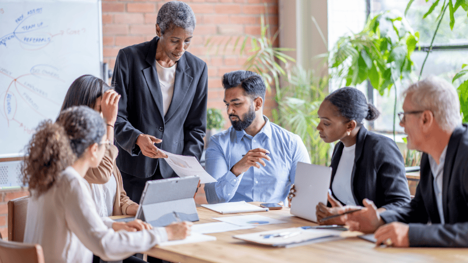 A group of people sitting around a table in an office, discussing a report
