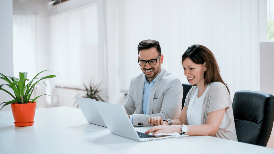 Two people working on laptops at a table