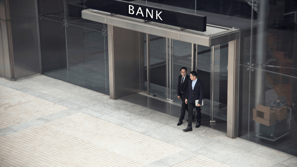 Two businesspeople standing in front of a bank entrance