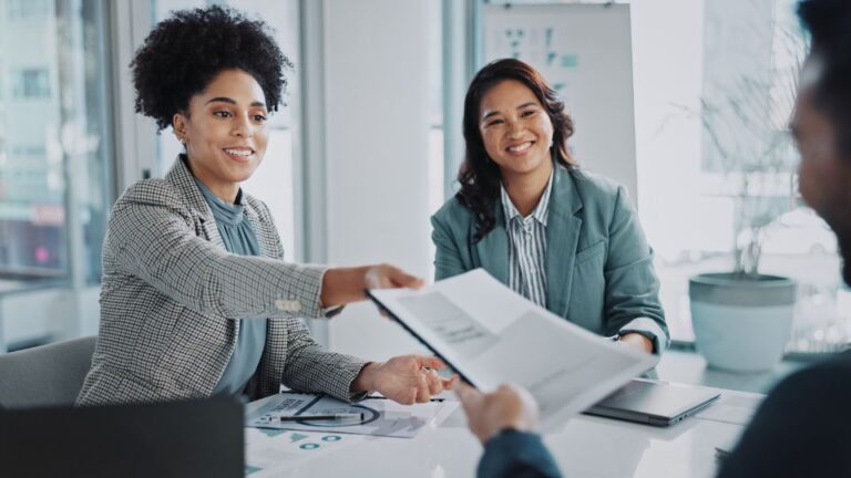 Two individuals shaking hands in an office meeting.
