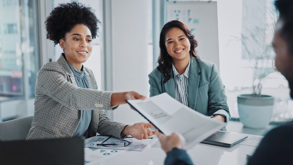 Two individuals shaking hands in an office meeting.
