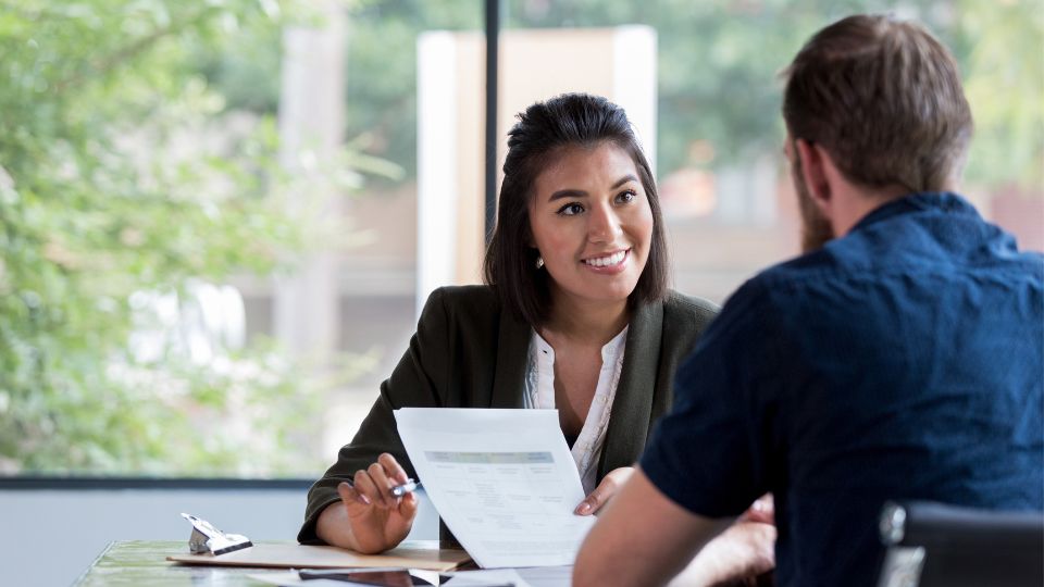 An attorney and a client are sitting across from one another and discussing a document.
