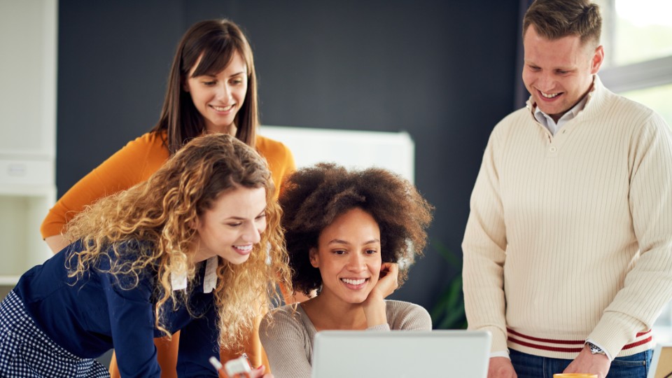 A group of people looking at a laptop.