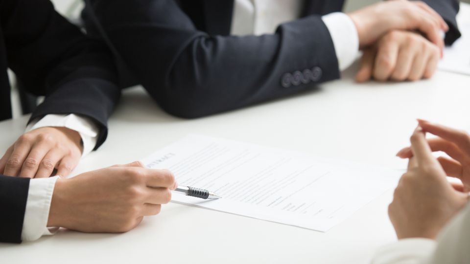 People sitting at a desk, reviewing a document.
