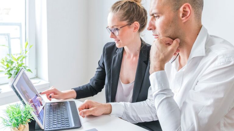 Two lawyers sitting at a desk and working on a laptop.