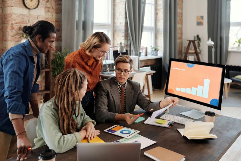 People in an office at a desk looking at a computer