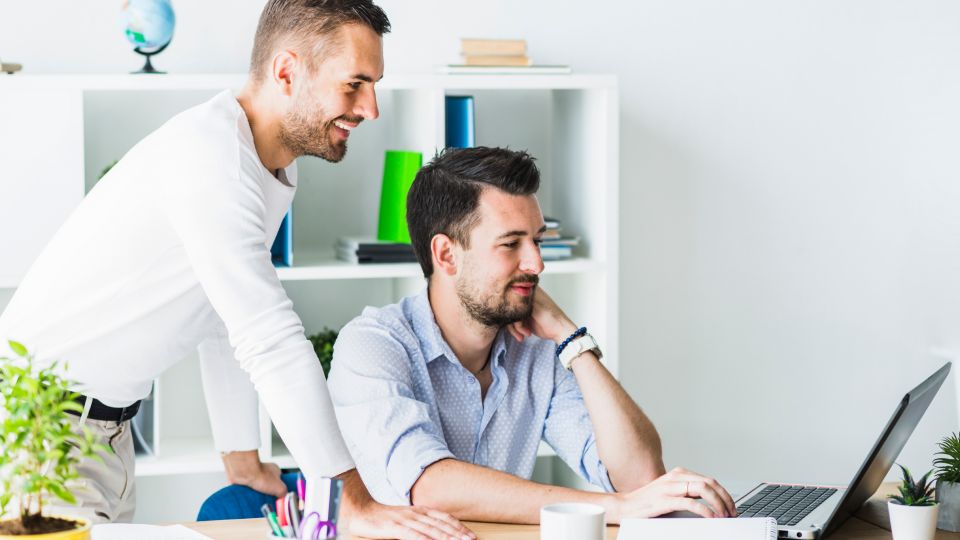 Two people reviewing something on a laptop in an office