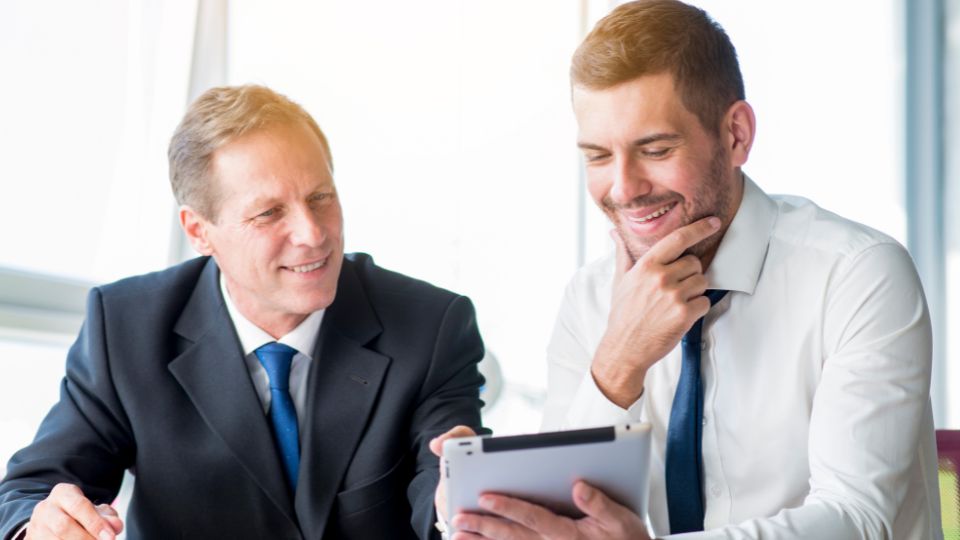 Two professionals working on a tablet in an office setting.