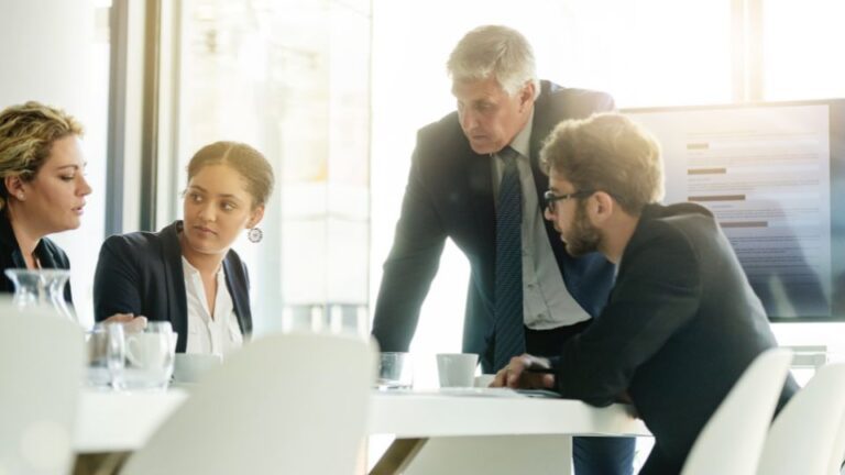 A group of colleagues having a conversation in a conference room.