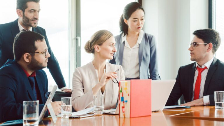 A group of people working together with laptops and documents on a table.