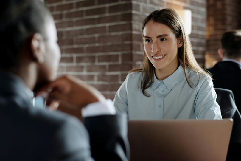 Two people having a conversation with a laptop in the foreground.