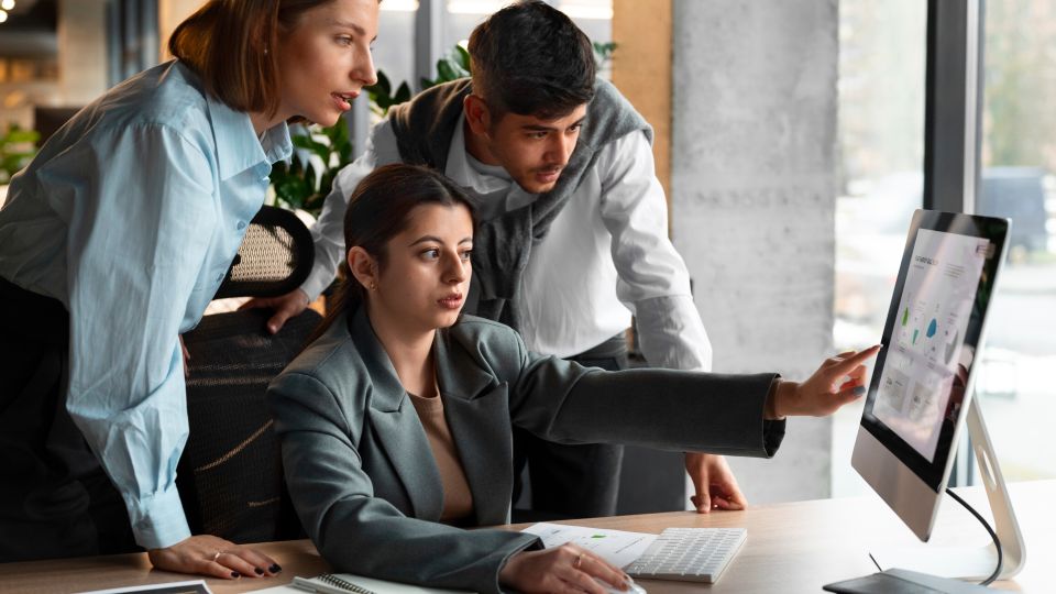 A group of colleagues looking at a computer and discussing the metrics on the screen