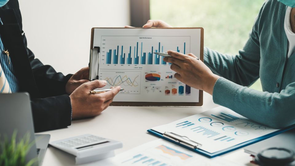 A close-up of two colleagues looking at a graph on a clipboard.