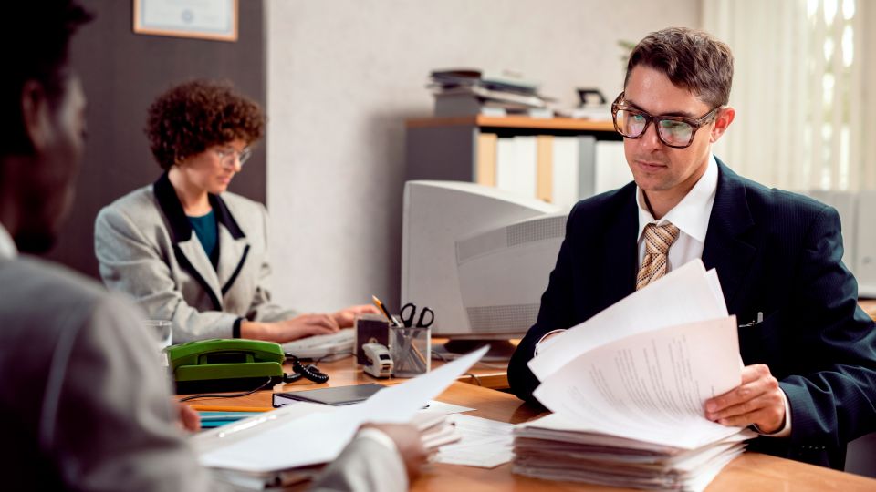A business professional reviews a stack of papers in an office