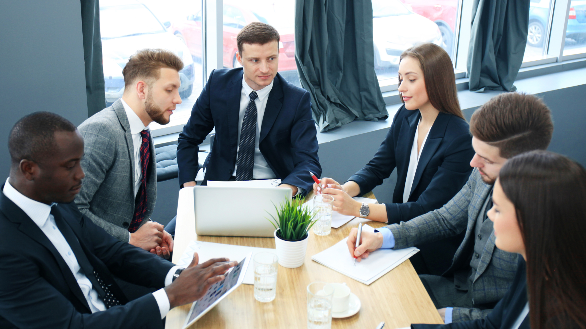 A group of young professionals gather around a table for a meeting.