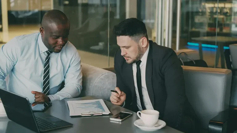 Two business persons reviewing a printed report together in a conference room.