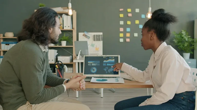 Two business persons reviewing a digital dashboard together at a desk.